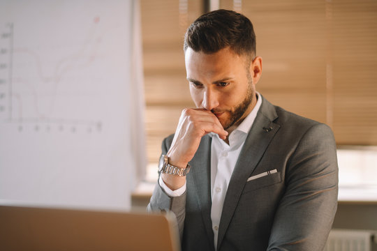 Portrait of handsome businessman in office. Worried businessman working on laptop in office .