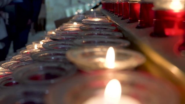 Detail of red candles in the machine inside a cathedral, wishes and prayers to the saints represented