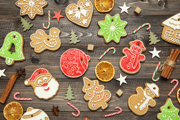 Christmas gingerbread cookies with candies, cinnamon and sugar cubes on brown wooden table