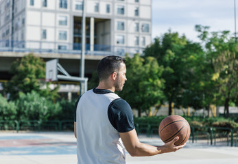 Fototapeta premium Sportsman plays basketball on an outdoor court on a very sunny day