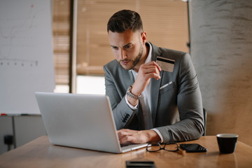 Paying bills online. Businessman in office. Handsome businessman using e-banking.  