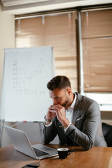 Portrait of handsome businessman in office. Worried businessman working on laptop in office .