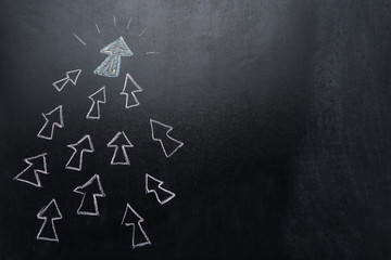 Leader concept. White arrows drawn on blackboard