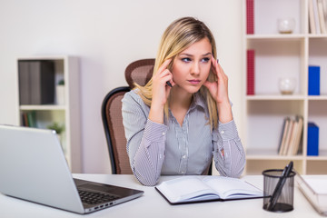 Businesswoman having headache while working in her office.
