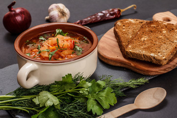 Ukrainian traditional borsch with rye bread on black background.