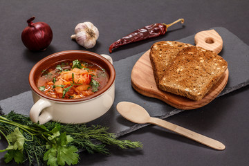 Ukrainian traditional borsch with rye bread on black background.