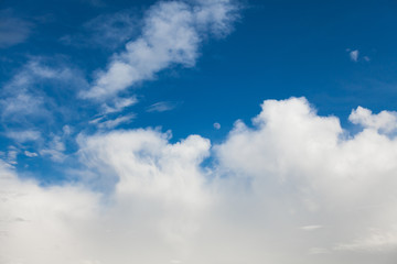 Background of white cumulus clouds with moon on a blue sky at daylight. Telephoto zoom shoot