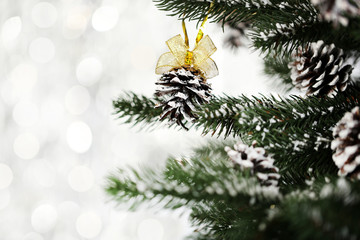 Christmas fir tree with cones on blurred lights background