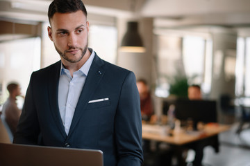 Portrait of handsome businessman. Man with his lap top in office. 