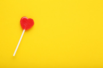 Heart shaped lollipop on yellow background