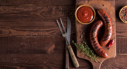 Grilled sausages on cutting board and wooden background