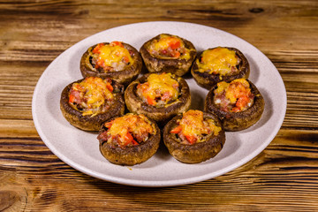 Baked champignons stuffed with minced meat and cheese in plate on a wooden table
