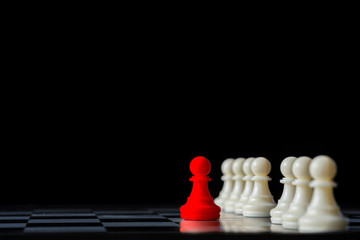 Red chess standing out from white chess on chess board and black background. Leadership concept.