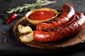 Grilled sausages on cutting board and black background