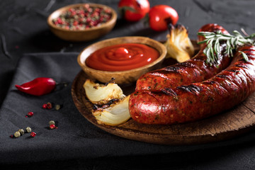Grilled sausages on cutting board and black background