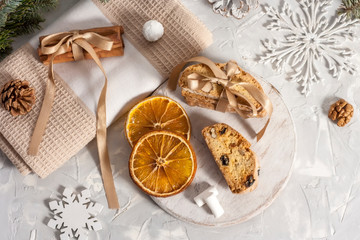 Cinnamon sticks are tied with a ribbon on a beige napkin with slices of dried orange, pine cone, nuts, snowflakes and marshmallows near a fir branch. Christmas concept. Top view