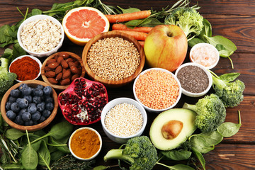 Healthy food clean eating selection: fruit, vegetable, seeds, superfood, cereals, leaf vegetable on rustic background
