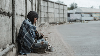 Street musician beggar playing guitar to ask for money of food from kind people. Old Asian homeless man begging for money.