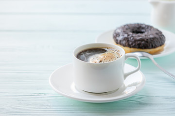 Classic black coffee in a white cup and a chocolate donut light background. Selective focus. Copy space horizontal frame