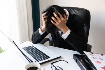 Business man holding his head problems debts in the office