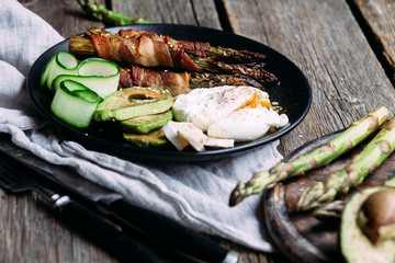 Baked asparagus in bacon with egg, avocado and cheese