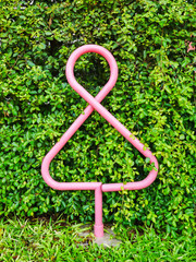 Public toilet graphic sign, Female rest room outdoor symbol made from round steel pipe post with green tree wall background