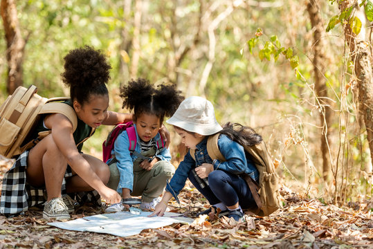 Group family children checking map for explore and find directions in the camping jungle nature and adventure. Tourism kids travel for destination and leisure trips for education and relax in nature 