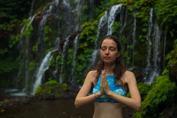 Close up of namaste mudra. Young woman meditating, practicing yoga and pranayama with gyan mudra near waterfall. Banyu Wana Amertha waterfall Wanagiri, Bali.