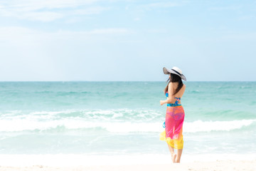 Summer Holiday. Lifestyle woman chill holding big white hat and wearing bikini fashion summer trips walking on the sandy ocean beach. Happy woman enjoy and relax vacation. Lifestyle and Travel Concept