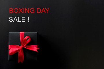 Boxing day sale online shopping.,Top view of black christmas gift boxes with red ribbon and text on black background with copy space for text.