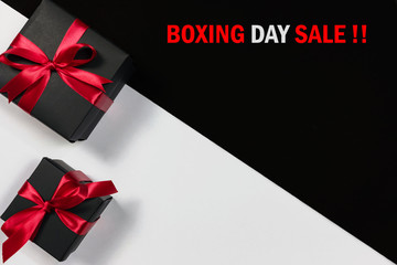 Fototapeta na wymiar Boxing day sale online shopping.,Top view of black christmas gift boxes with red ribbon and text on black and white background with copy space for text.