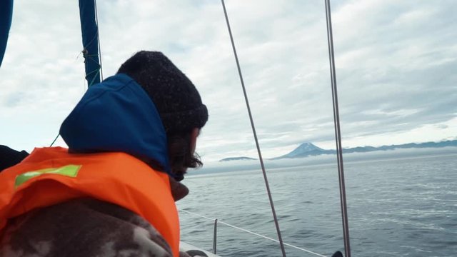 Tourist in a life jacket on boat. Vilyuchinsky volcano (also called Vilyuchik) is visible in the background. Kamchatka