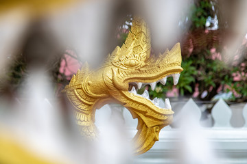 View of the gilded statue of Naga - dragon through teeth in the jaw of another Naga.