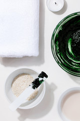 Spa,beauty cosmetics and body care treatment concept close-up.Creative top view flat lay composition ingredients green spirulina cleansing mask bowl on white background.Vertical orientation