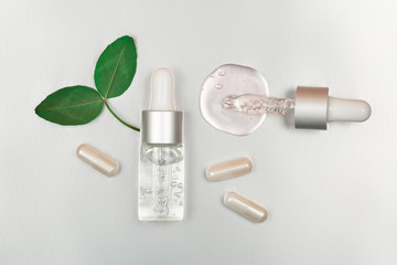 Bottle with hyaluronic acid on silver background. Concept of modern beauty. Flat lay style.