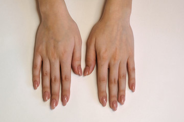 beautiful female hands with beige manicure on a white background