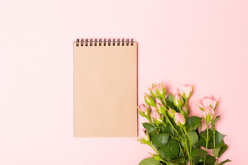 Mock up with pink roses and blank brown craft notebook.Minimalist flat lay, pink background.