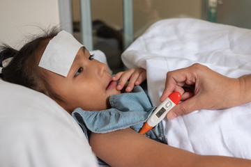 Sick child., Asian woman hand holding a digital thermometer to measure the temperature of a daughter. Health and medical concept.