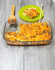 Salmon baked with potatoes under mayonnaise and cheese in a glass pan on a wooden table top view