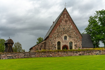 Fototapeta na wymiar View of a medieval stone church in Sweden with dark overcast clouds