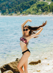 Cute girl in a black and pink swimsuit posing on the beach