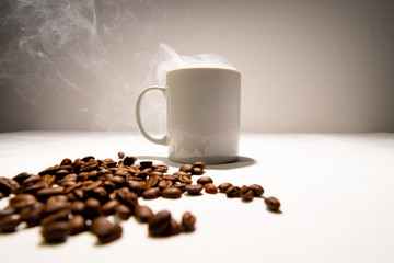 White coffee mug smoke coming out of the coffee cup. And coffee beans