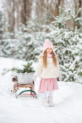 Fototapeta na wymiar Fairy tale a beautiful girl in a white fur coat rolls a sled in a winter snow covered forest with Christmas trees