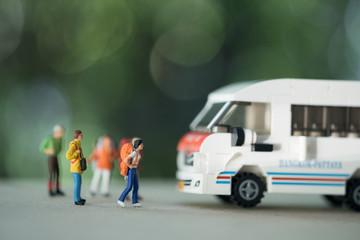 Close up of group of traveler miniature figure with backpack standing with mini toy van model.