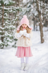 Fairy tale beautiful girl in a white fur coat pink hat snow in her hands