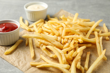 Tasty french fries, sauces on gray background, space for text. Closeup