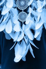 Dreamcatcher made of feathers, leather, beads, and ropes in classic blue trendy color of the year 2020.