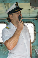 Navigation officer manage ship with transmitter. Captain standing in the wheelhouse.