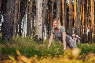 pretty young woman takes plank workout on a mat on nature. sport activity in the morning for strong health