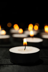 Obraz na płótnie Canvas Group of burning candles on black background, close up
